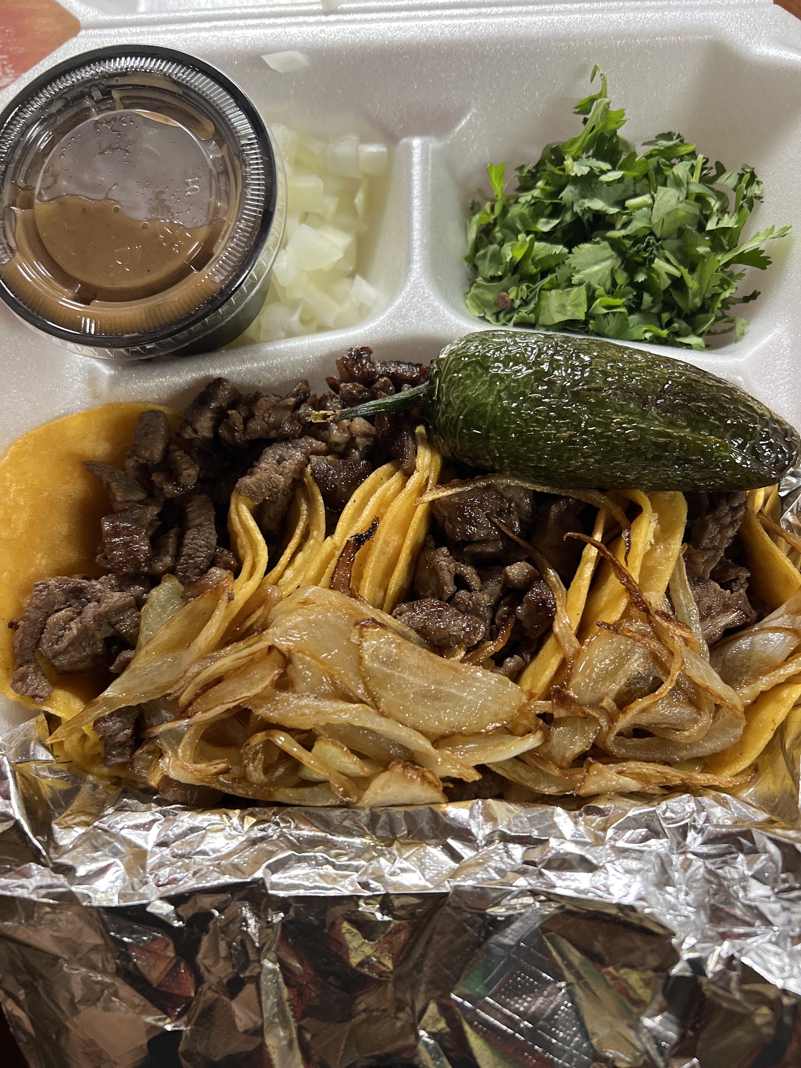 Carne asada street tacos with grilled onions and a jalapeño
